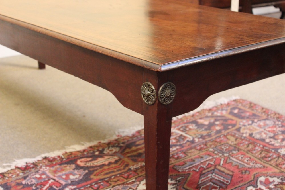 A long rectangular dark mahogany coffee table featuring a polished surface, shaped aprons with circular brass rosette mounts, and four square tapered legs. View III