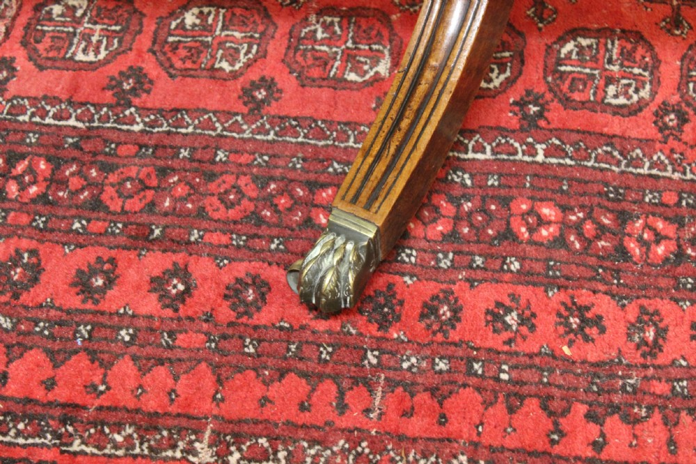 A Regency mahogany twin pillar dining table featuring reeded quadruped legs ending in brass castors and a polished rectangular top with rounded corners. View VI