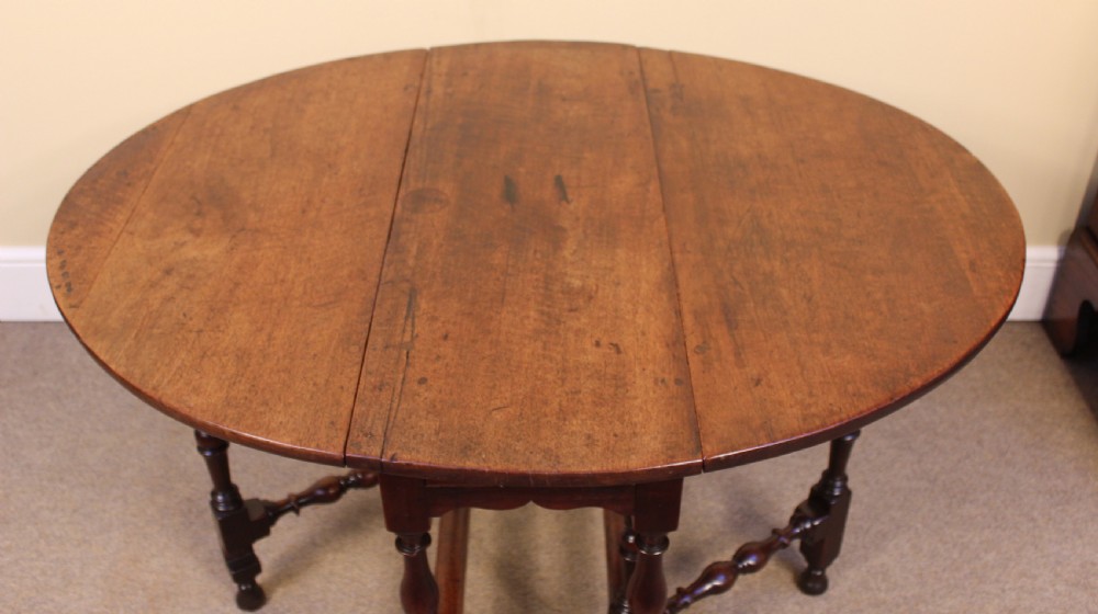 An early eighteenth-century walnut gate leg table featuring baluster-turned legs, a stretcher base, a single drawer, and two drop leaves. View II