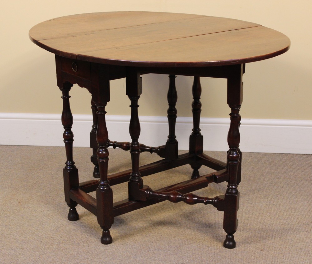 An early eighteenth-century walnut gate leg table featuring baluster-turned legs, a stretcher base, a single drawer, and two drop leaves. View III