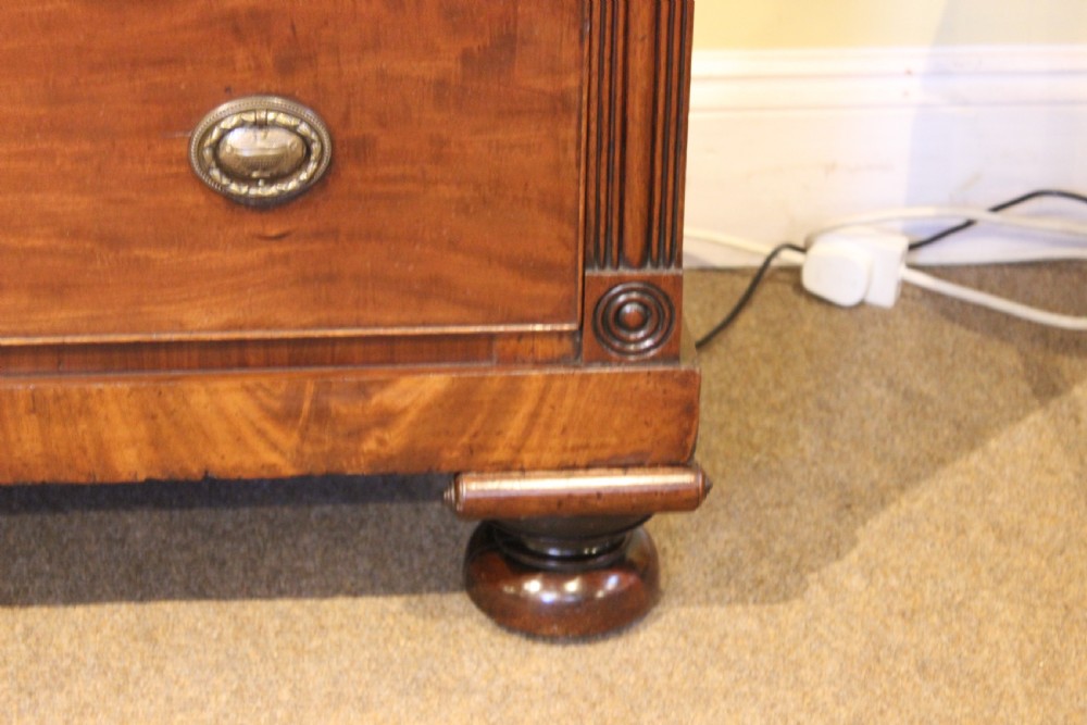 A nineteenth-century Scottish mahogany chest of drawers featuring three upper drawers over three long graduated drawers with reeded side columns and turned feet. View IV