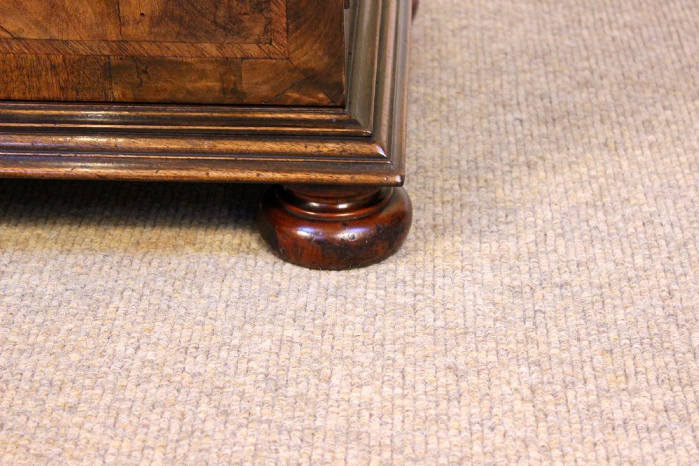 A 19th-century walnut side cabinet featuring twin book-matched veneer doors, moulded base, and turned bun feet. View V