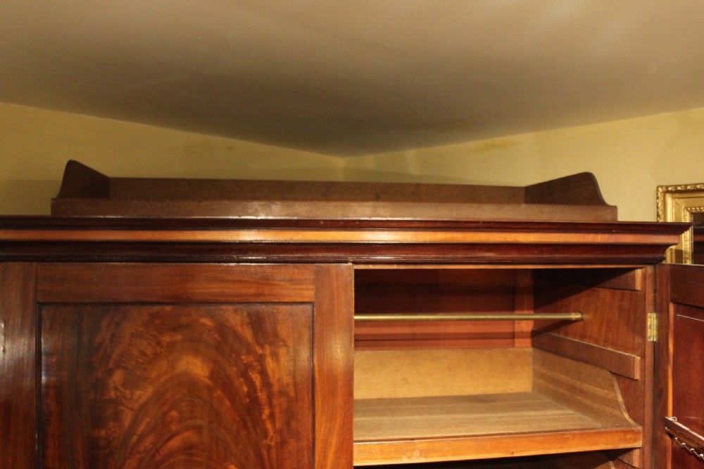 An early 19th-century flame mahogany linen press with twin panelled doors above three long drawers resting on bracket feet. View V