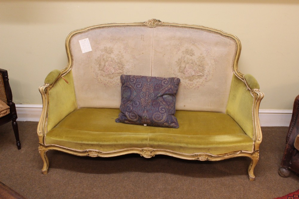 A late nineteenth-century French style upholstered sofa featuring a cream painted wooden frame with carved details, an olive green velvet seat, and a padded tapestry backrest. View II
