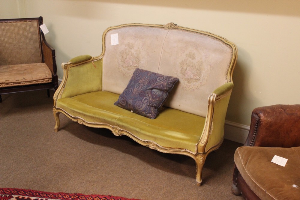 A late nineteenth-century French style upholstered sofa featuring a cream painted wooden frame with carved details, an olive green velvet seat, and a padded tapestry backrest. View IV
