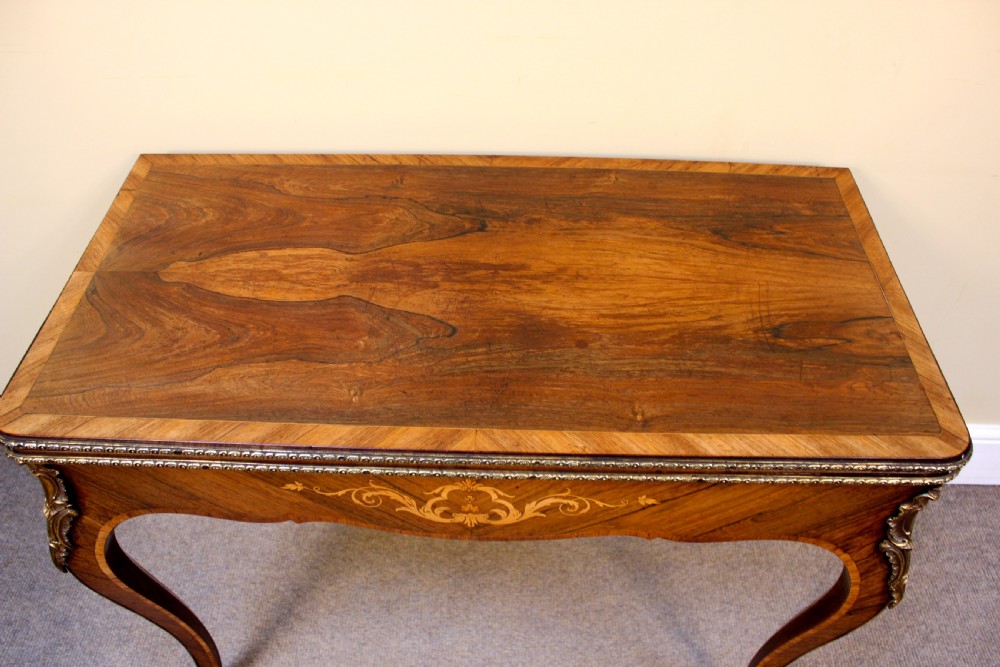 A 19th-century rosewood card table featuring kingwood crossbanding, central marquetry inlay, cabriole legs, and brass shoulder mounts. View III