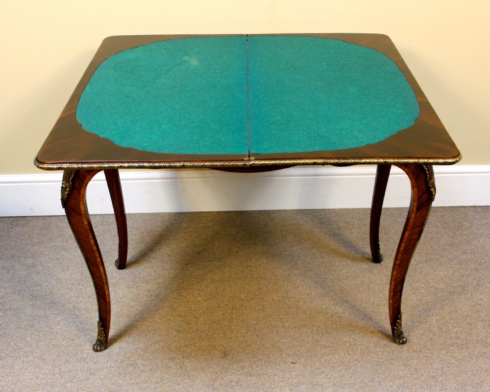 A 19th-century rosewood card table featuring kingwood crossbanding, central marquetry inlay, cabriole legs, and brass shoulder mounts. View VII