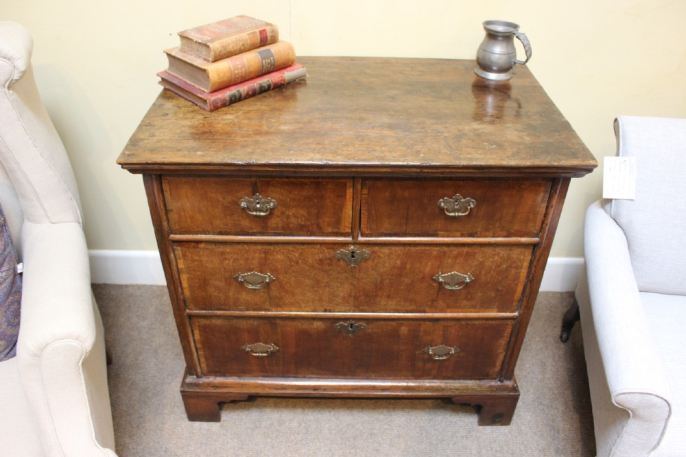 An 18th-century walnut and ash chest of drawers featuring two short over two long drawers with brass drop handles and bracket feet. View III