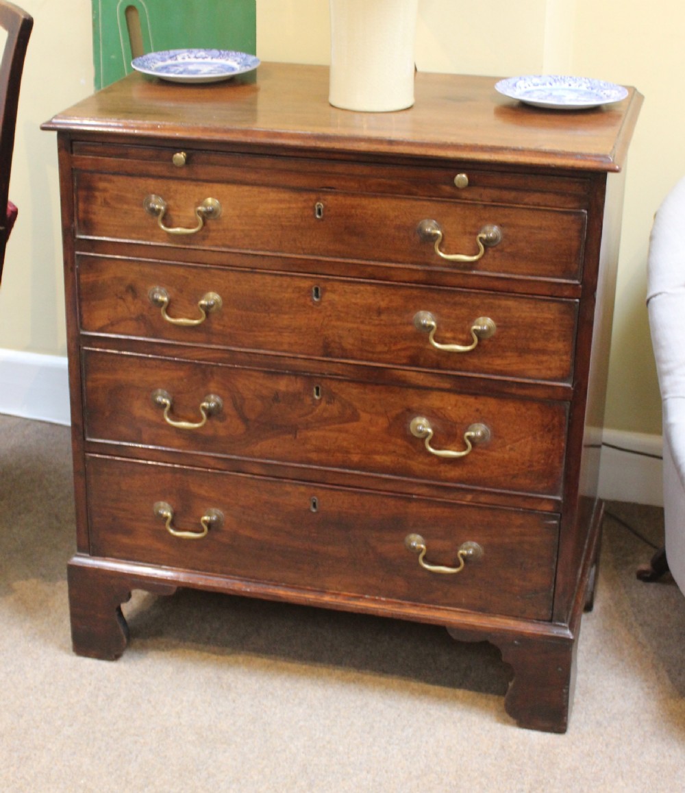 An early nineteenth-century mahogany bachelors chest of drawers featuring four graduated drawers with brass handles and bracket feet.