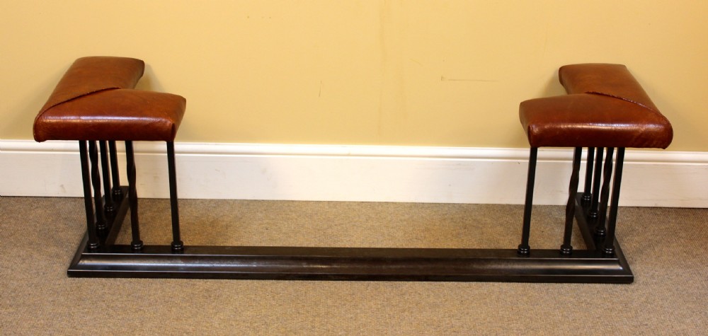 An early 20th-century dark steel club fender featuring vertical support spindles and twin corner seats upholstered in brown leather. View II