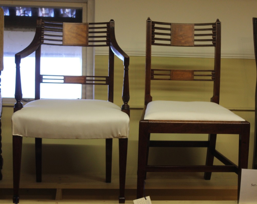 A set of nineteenth-century mahogany dining chairs featuring slatted backs with marquetry inlay panels and cream fabric seats.