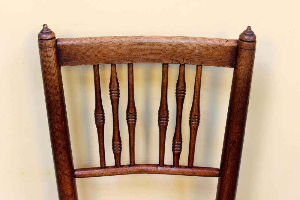 A 19th-century country kitchen chair crafted from dark ash and elm, featuring turned spindle backrest slats, a contoured solid timber seat, and turned front stretchers. View V
