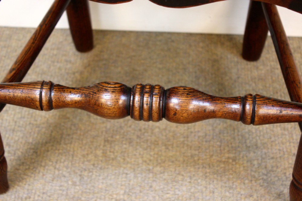 A 19th-century country kitchen chair crafted from dark ash and elm, featuring turned spindle backrest slats, a contoured solid timber seat, and turned front stretchers. View VII