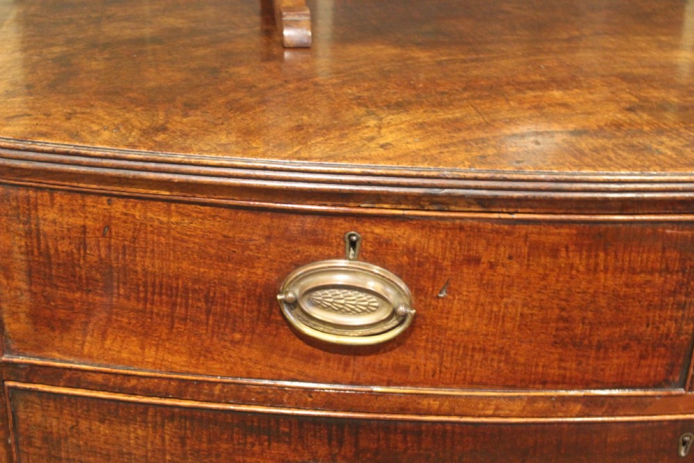 A nineteenth-century mahogany bow-fronted chest of drawers featuring two short and three long drawers with oval brass handles. View IV