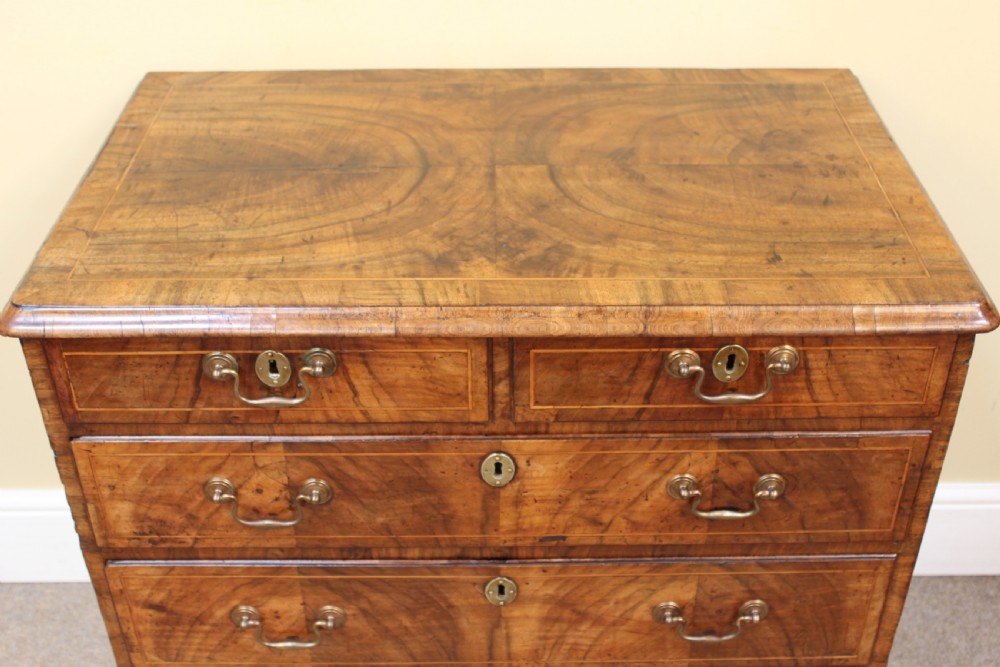 An early 18th-century George I walnut chest of drawers featuring two short over three long drawers, crossbanded drawer fronts, brass drop handles, and bracket feet. View III