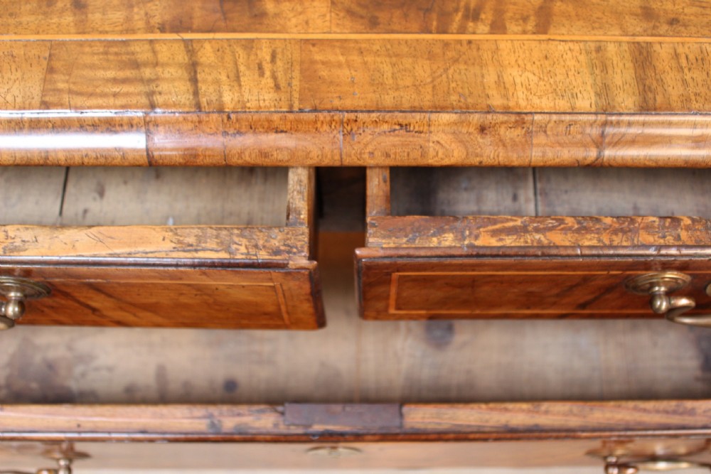 An early 18th-century George I walnut chest of drawers featuring two short over three long drawers, crossbanded drawer fronts, brass drop handles, and bracket feet. View IV