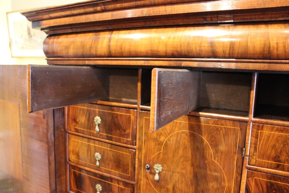 An 18th-century walnut cabinet on stand featuring double doors with book-matched veneer panels, a lower drawer base, and six barley-twist legs joined by a wavy stretcher. View VI