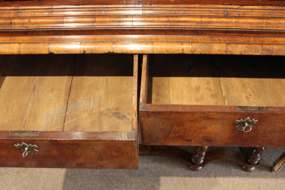 An 18th-century walnut cabinet on stand featuring double doors with book-matched veneer panels, a lower drawer base, and six barley-twist legs joined by a wavy stretcher. View VII