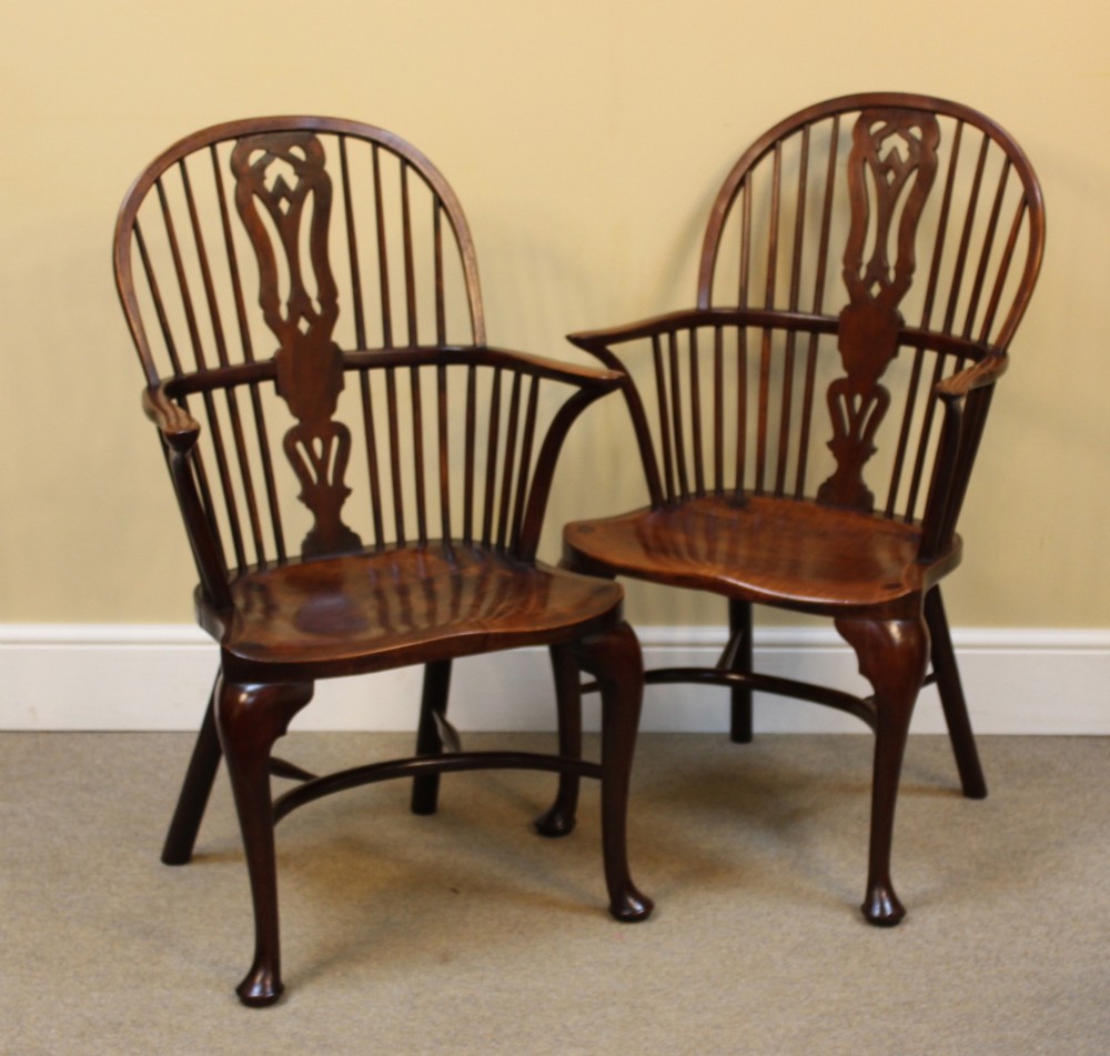 A pair of nineteenth-century yew and elm Windsor armchairs featuring steam-bent hoop backs, pierced central splats, contoured seats, and cabriole front legs.
