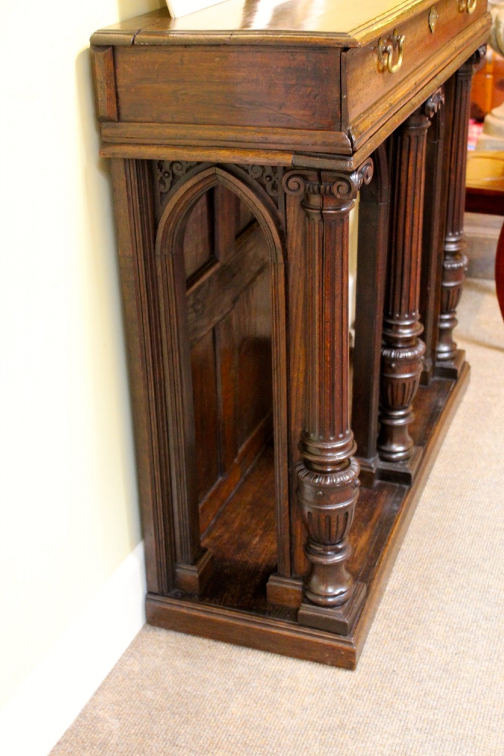 An 18th-century dark oak side table featuring a single top drawer with brass handles above twin open arched bays framed by fluted columns. View III