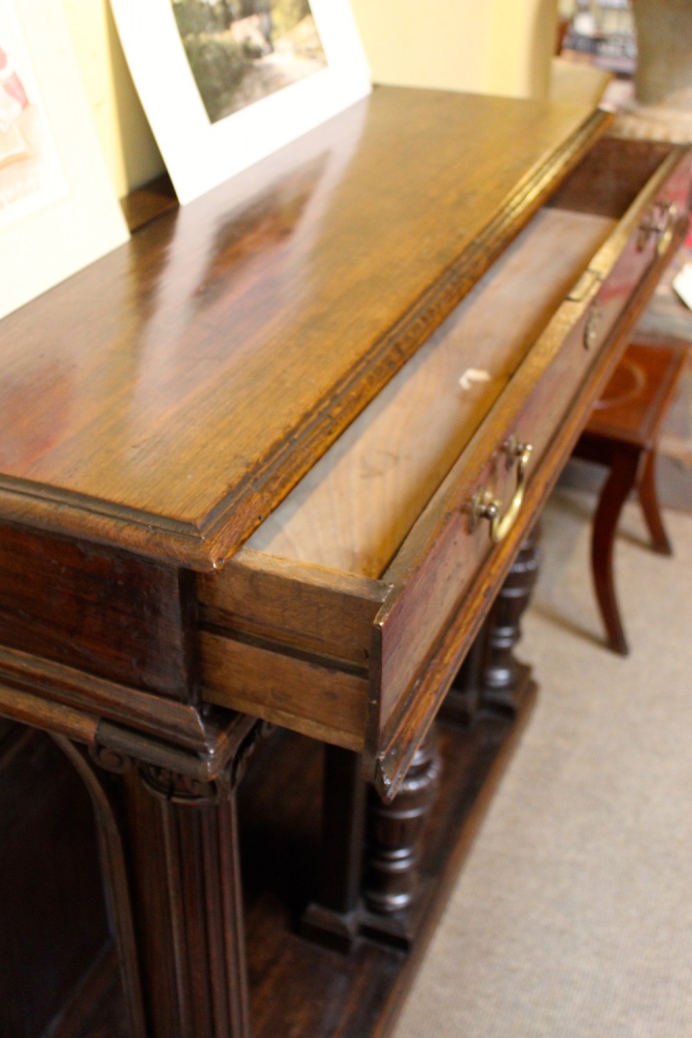 An 18th-century dark oak side table featuring a single top drawer with brass handles above twin open arched bays framed by fluted columns. View IV
