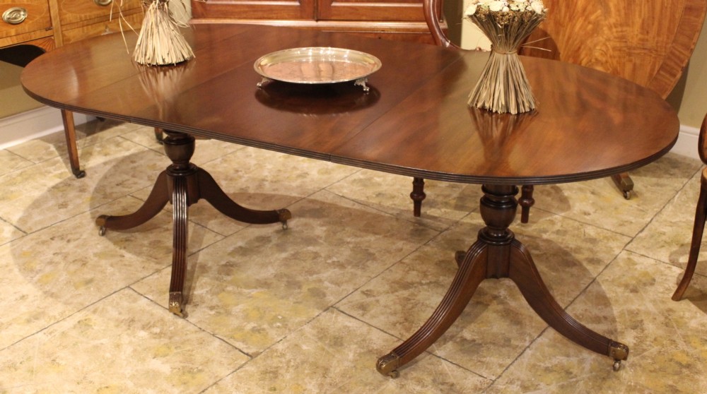 A 19th-century mahogany D-end extending dining table supported on twin turned pedestals with reeded splayed legs and brass castors.