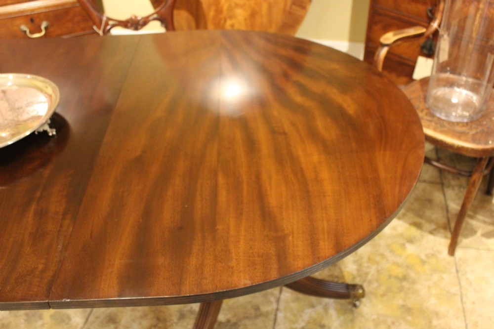 A 19th-century mahogany D-end extending dining table supported on twin turned pedestals with reeded splayed legs and brass castors. View III