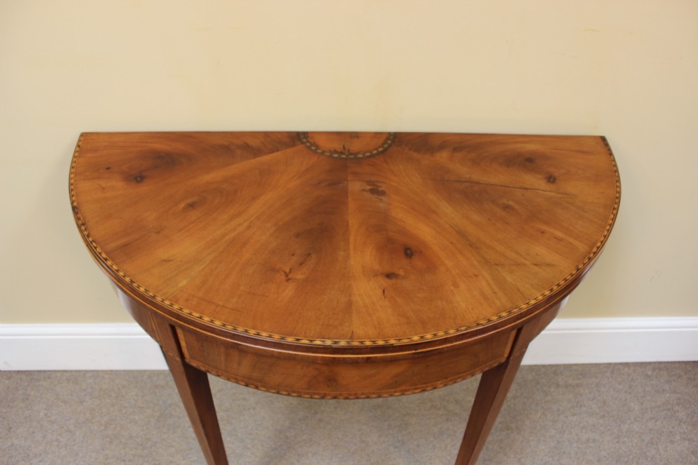 A 19th-century mahogany and fruitwood demi-lune card table featuring fan veneer inlays on the folding top and four tapered legs. View IV