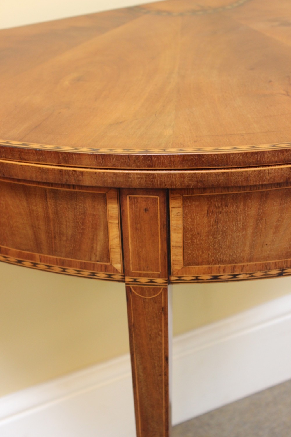 A 19th-century mahogany and fruitwood demi-lune card table featuring fan veneer inlays on the folding top and four tapered legs. View V