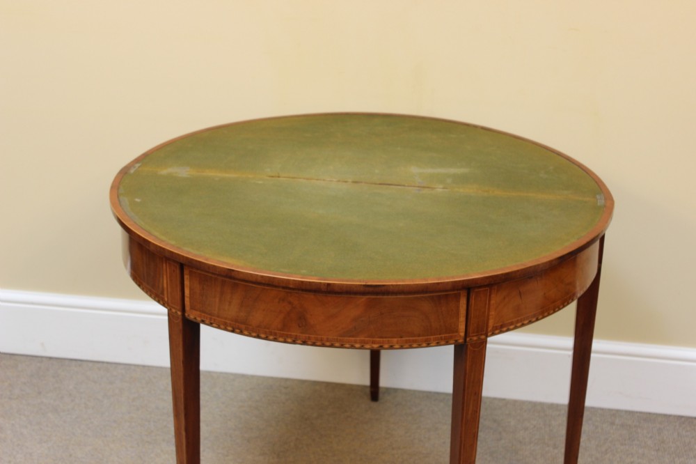 A 19th-century mahogany and fruitwood demi-lune card table featuring fan veneer inlays on the folding top and four tapered legs. View VI