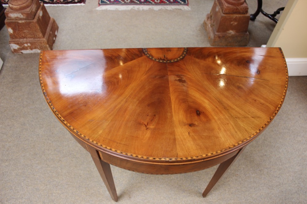 A 19th-century mahogany and fruitwood demi-lune card table featuring fan veneer inlays on the folding top and four tapered legs. View IX