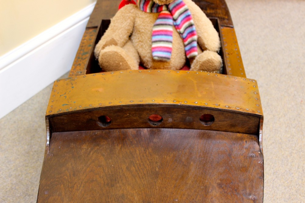 An Edwardian childs model speedboat crafted from brown patinated metal with riveted detailing, dashboard portholes, and a red interior seat. View VI
