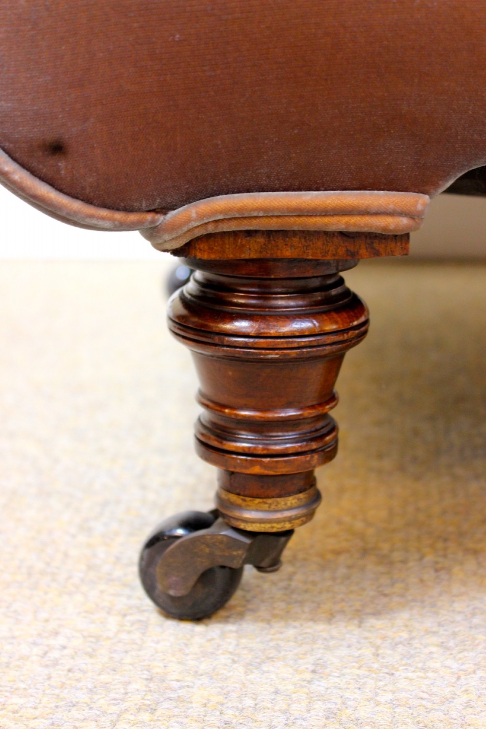 A 19th-century low-seated armless slipper chair upholstered in bronze brown fabric with button tufting on turned walnut legs with castors. View IV