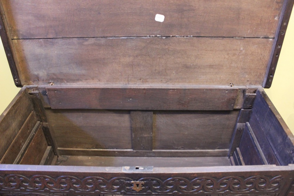 A dark carved oak coffer featuring three arcaded panels with carved floral details and a brass escutcheon. View VII