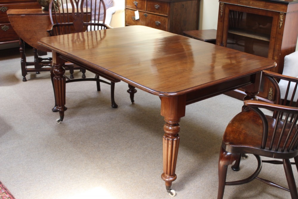 A nineteenth-century mahogany extending dining table with a polished rectangular top, rounded corners, and fluted turned legs on brass castors.