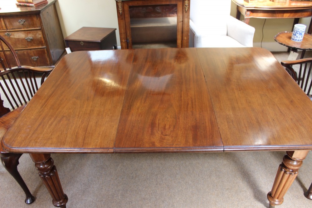 A nineteenth-century mahogany extending dining table with a polished rectangular top, rounded corners, and fluted turned legs on brass castors. View III
