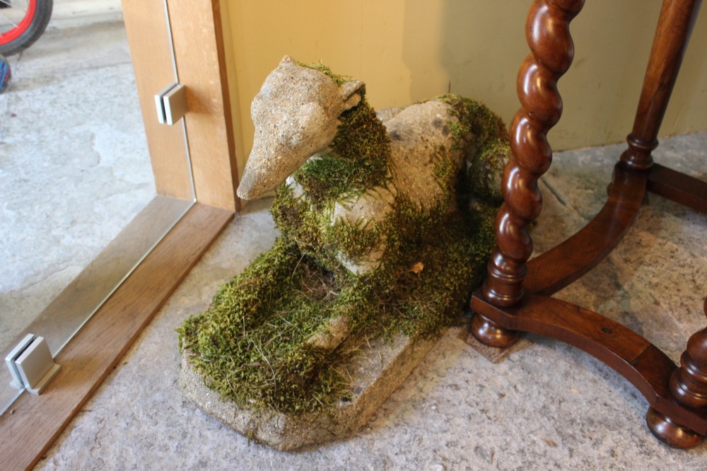 A pair of early 20th-century weathered cast stone statues depicting reclining whippets with natural moss growth on their surface. View III