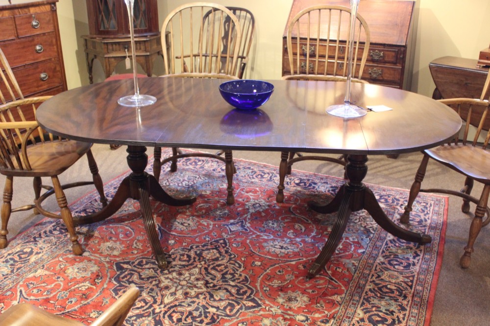 A late nineteenth-century mahogany twin-pillar dining table featuring an oval top supported by two turned pedestals with splayed reeded tripod legs. View II