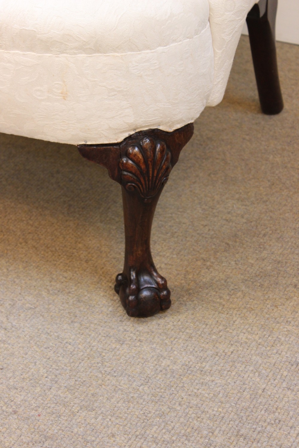 A 19th-century wingback armchair upholstered in cream patterned fabric featuring carved dark walnut cabriole front legs. View V