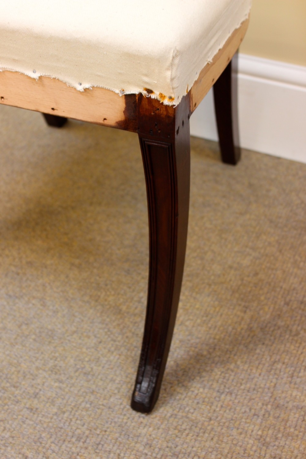 A nineteenth-century mahogany dining chair featuring a carved scroll crest rail, open back, cream upholstered seat, and tapered legs. View V