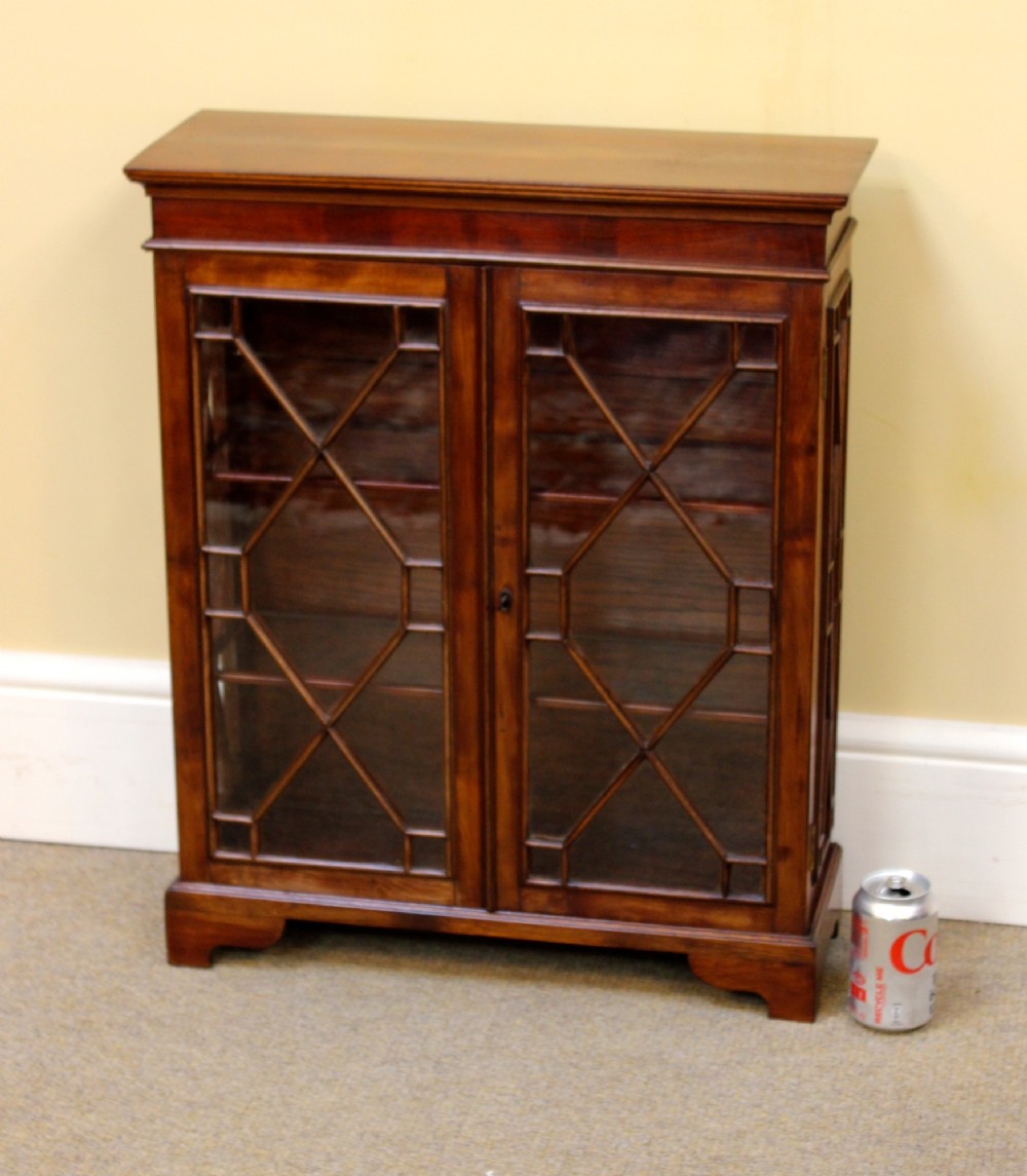 A 19th-century miniature mahogany display cabinet featuring twin astragal glazed doors and bracket feet.