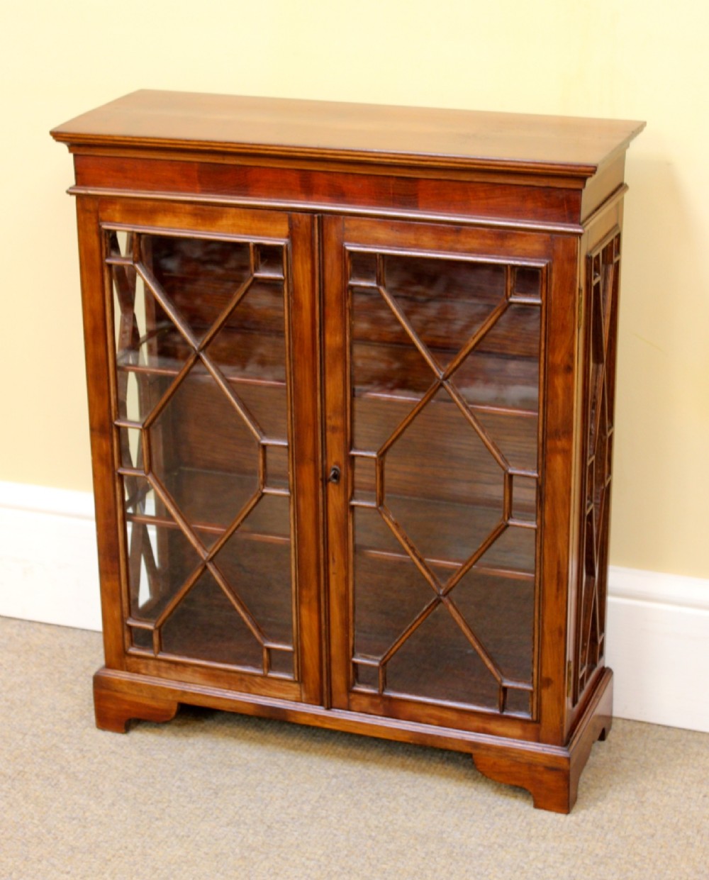 A 19th-century miniature mahogany display cabinet featuring twin astragal glazed doors and bracket feet. View III