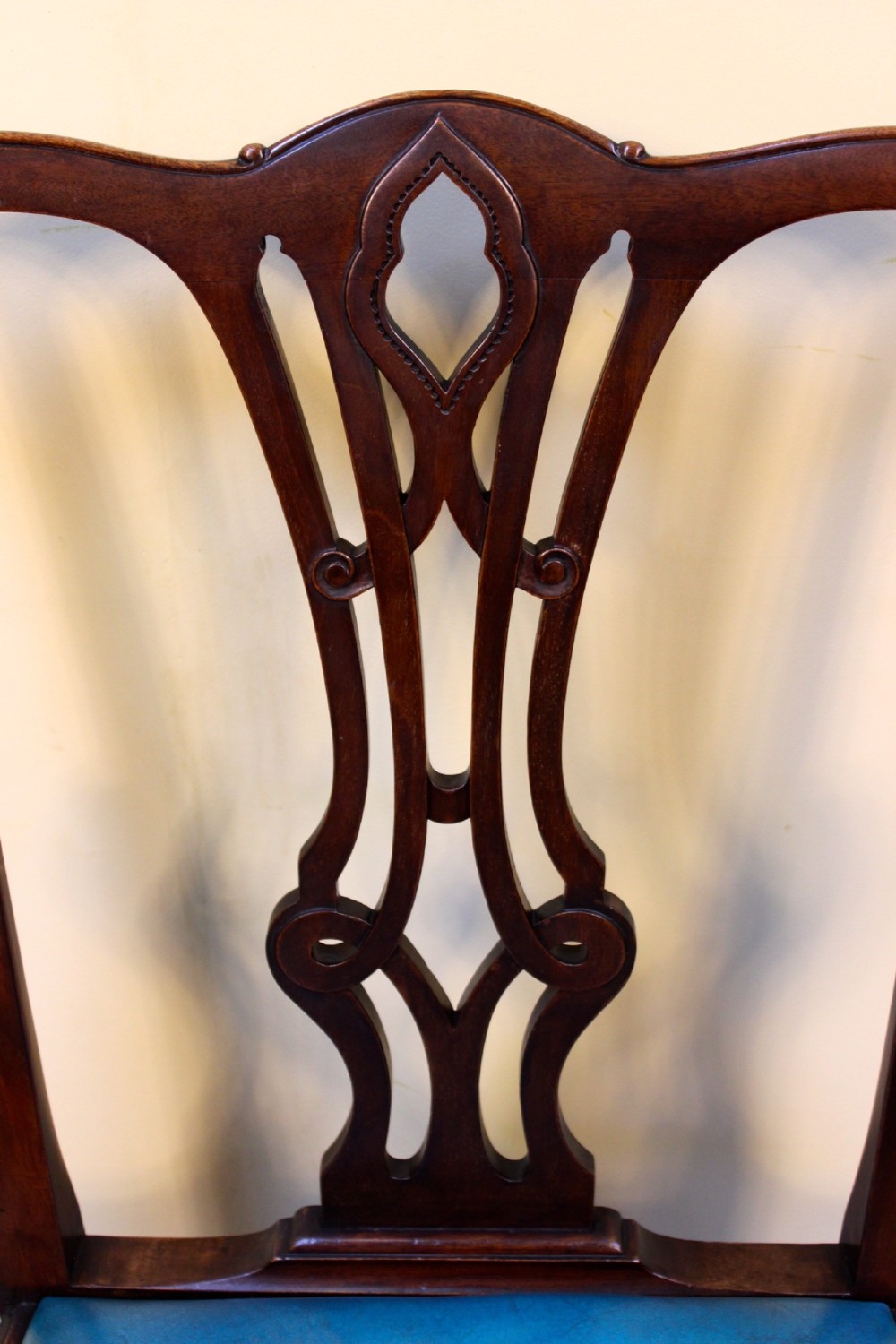 A pair of 19th-century Chippendale style mahogany dining chairs featuring carved pierced back splats, square legs with stretchers, and bright blue leather drop-in seats. View V