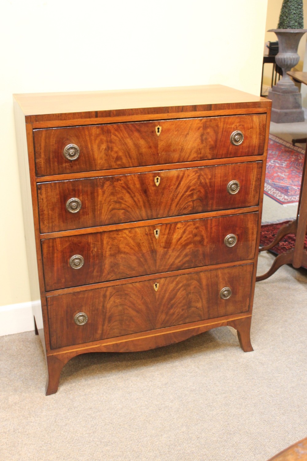 A nineteenth-century mahogany chest of four graduated drawers featuring flame mahogany grain and brass handles.