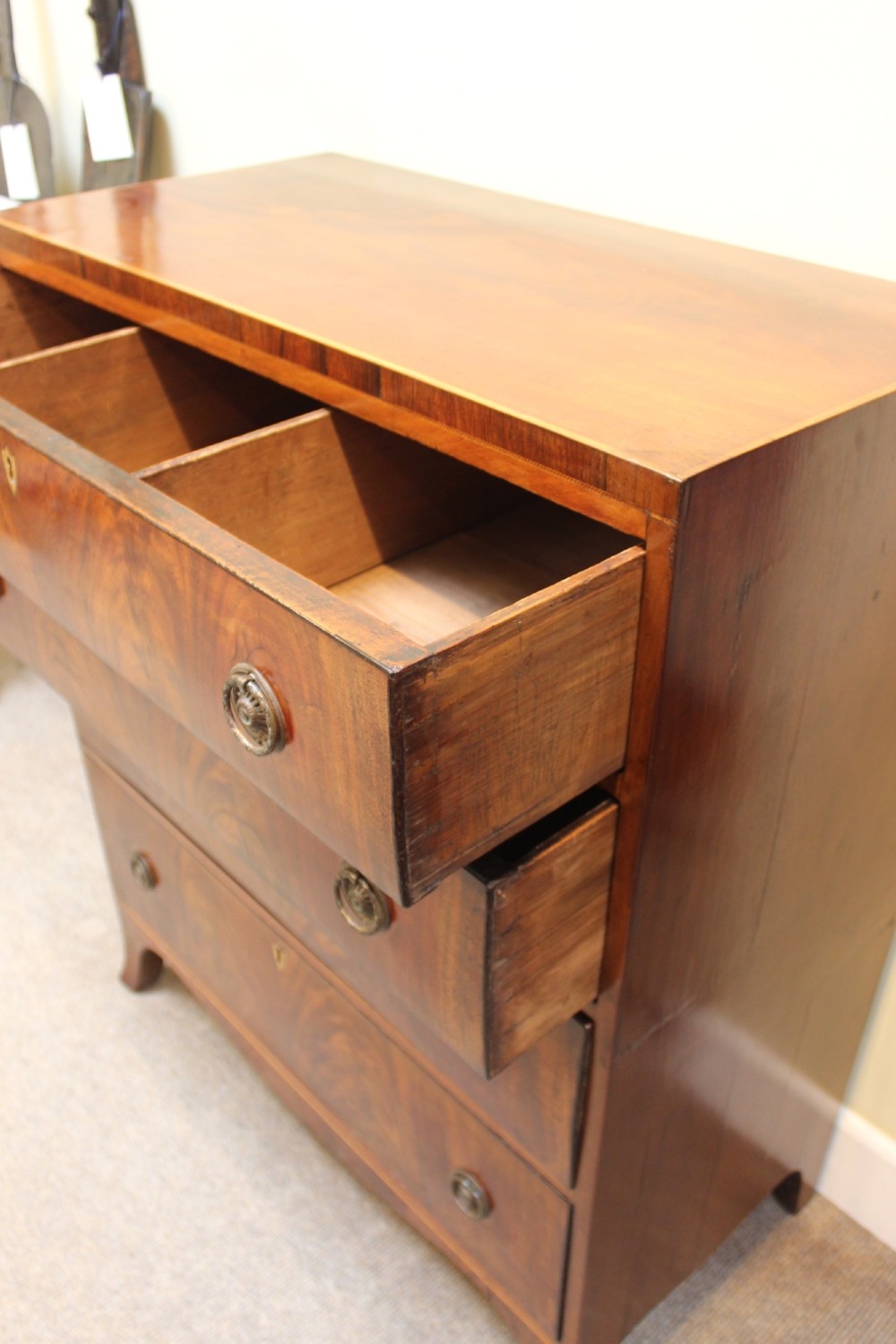 A nineteenth-century mahogany chest of four graduated drawers featuring flame mahogany grain and brass handles. View IV