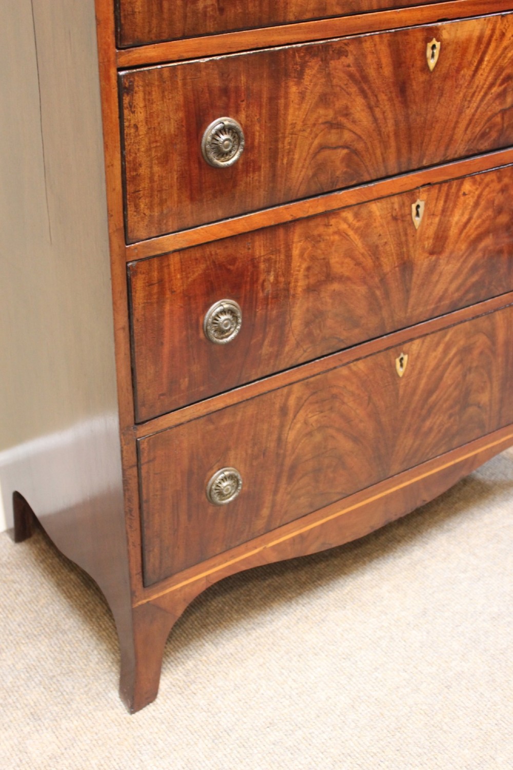 A nineteenth-century mahogany chest of four graduated drawers featuring flame mahogany grain and brass handles. View V