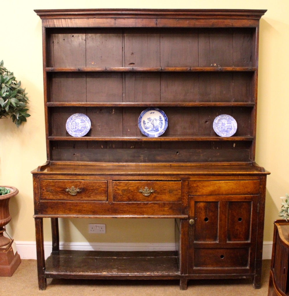 An 18th-century dark oak dresser featuring a multi-tier open plate rack above a drawer and cupboard base with a lower pot board.