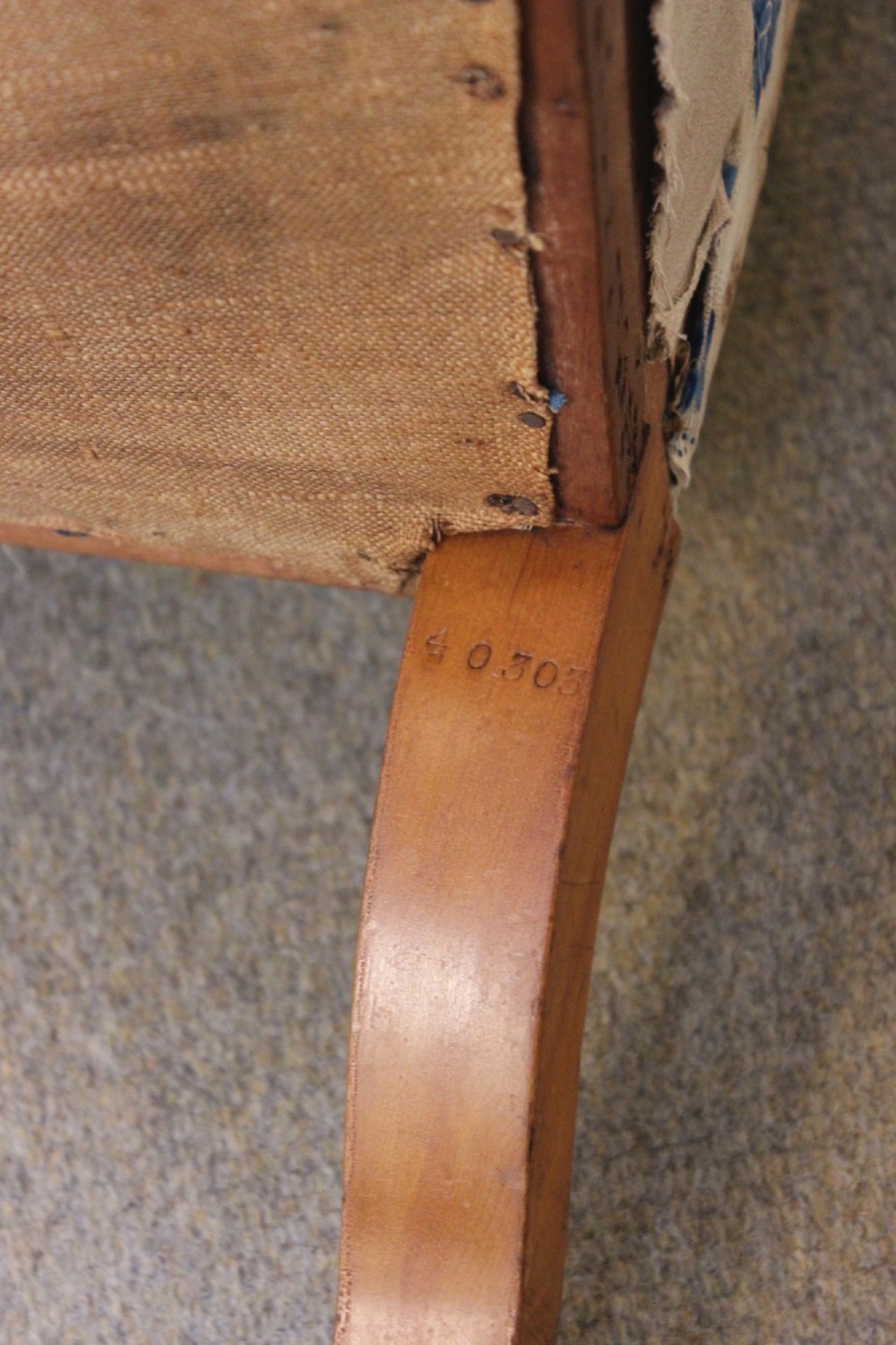 A 19th-century low-seated nursing chair with turned front legs on brass castors, a beige upholstered seat, and a curved backrest covered in blue floral fabric. View V