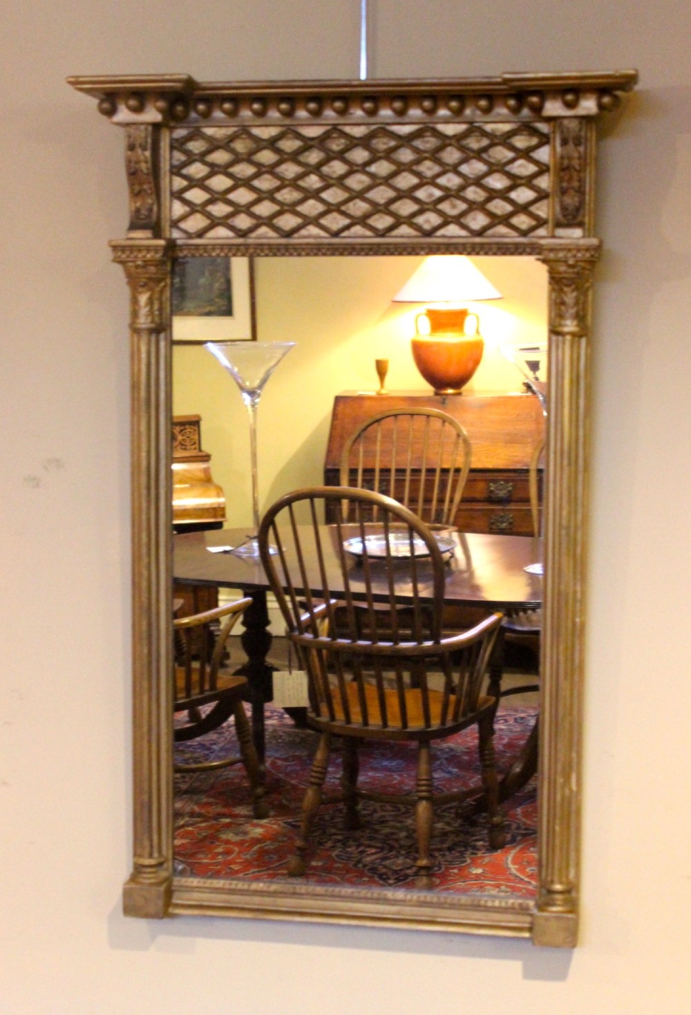 A tall 19th-century giltwood pier mirror featuring fluted side pilasters, a ball-moulded cornice, and a lattice pattern top frieze.