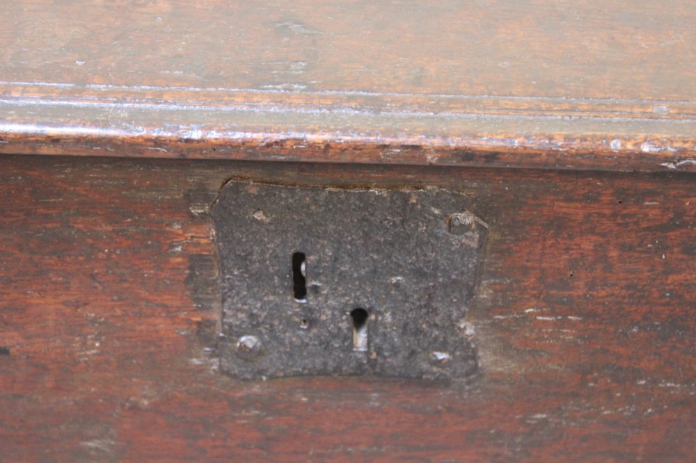 A 17th-century dark oak six-plank coffer featuring a hinged rectangular lid, hand-forged iron lockplate, and slab sides. View V